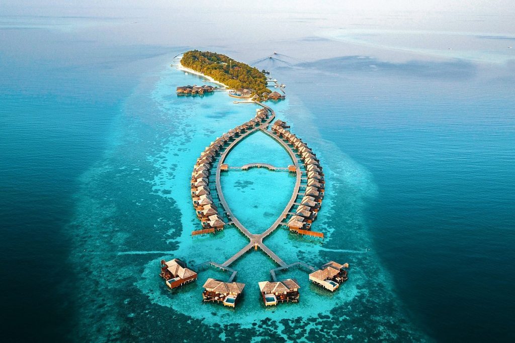 Aerial view of a luxury resort in South Ari Atoll, Maldives, showcasing crystal clear turquoise water and overwater villas.