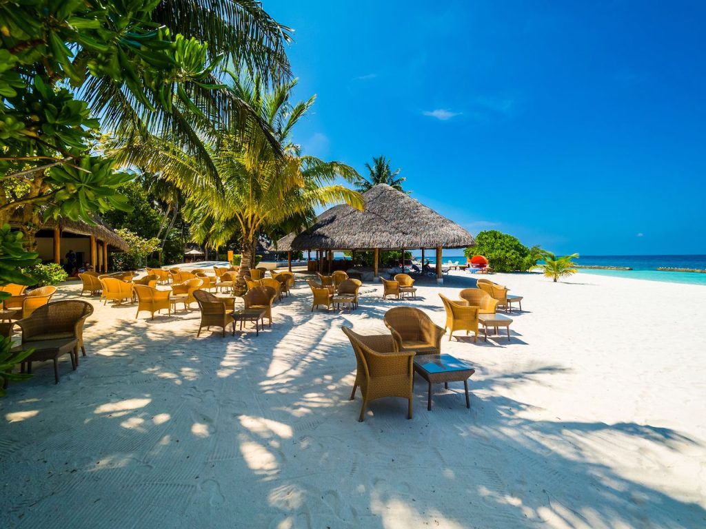 A budget traveler snorkeling in crystal clear water near a local Maldivian island like Maafushi.