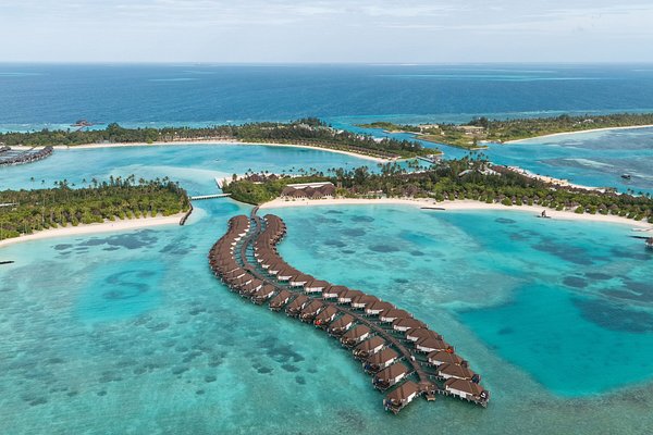 Aerial view of a luxury island resort in South Malé Atoll, Maldives, showing turquoise lagoons and overwater villas.