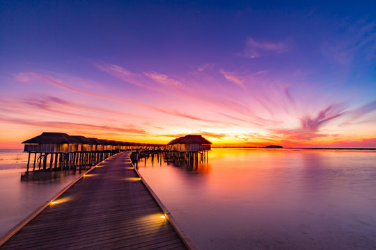 Golden sunset view over affordable overwater bungalows in Maldives for budget travelers.