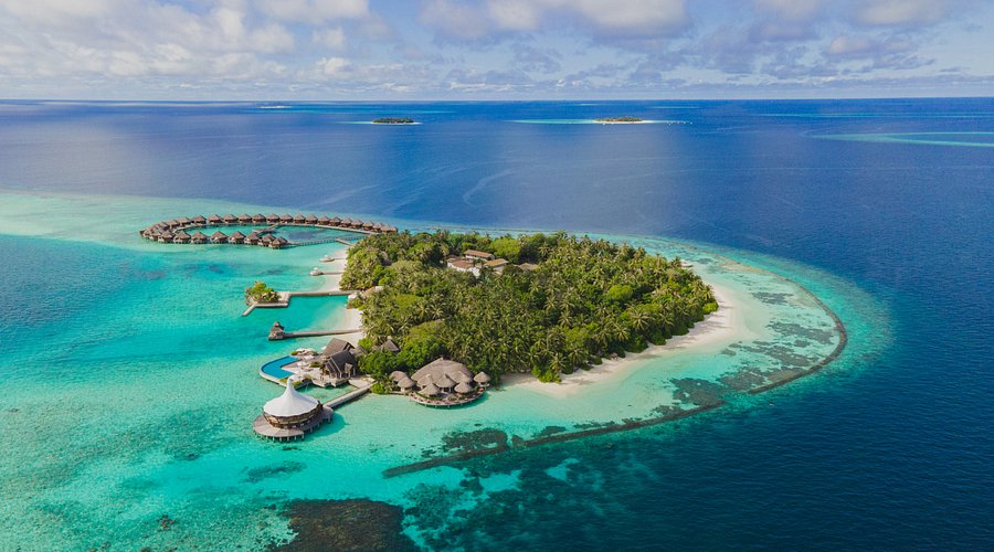 Aerial view of Baros Maldives luxury resort featuring overwater villas, crystal clear turquoise lagoon, and lush tropical greenery for a perfect honeymoon.
