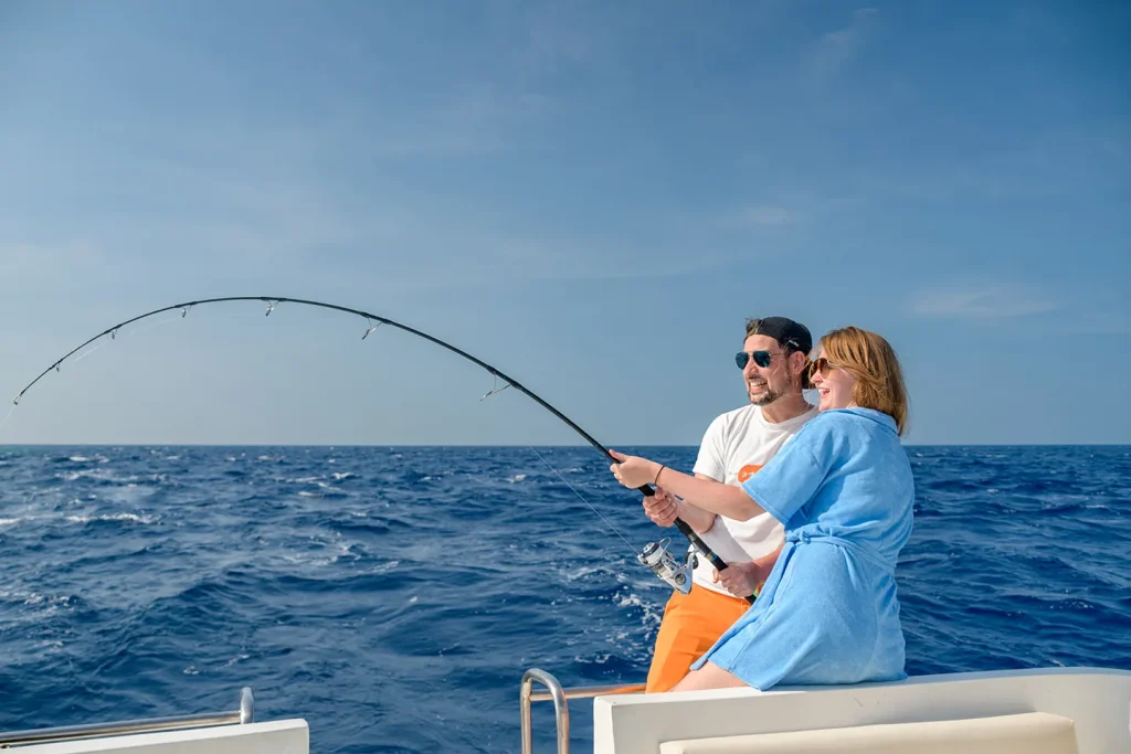 A couple enjoying big game fishing on a boat in the deep blue waters of the Maldives during an adventure trip.