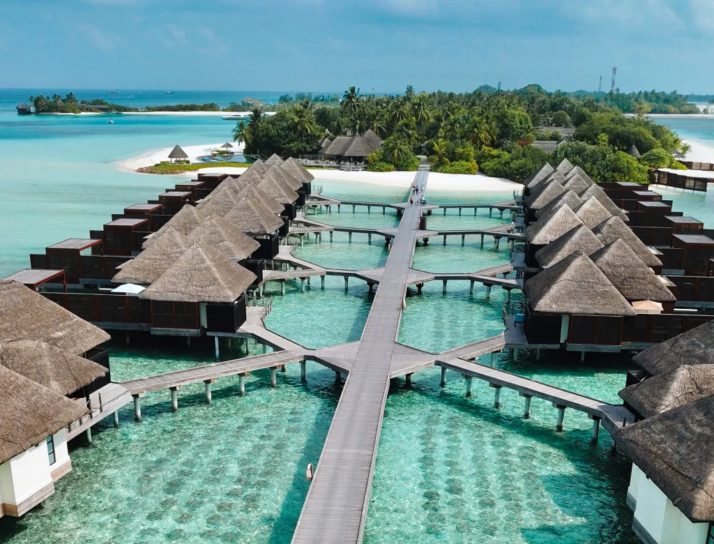 Aerial view of luxury overwater bungalows at a family-friendly resort in the Maldives with crystal clear turquoise water.