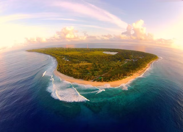 Aerial view of Fuvahmulah island in the Maldives showing lush green vegetation, white sandy beaches, and turquoise ocean waves—a hidden gem beyond luxury resorts.