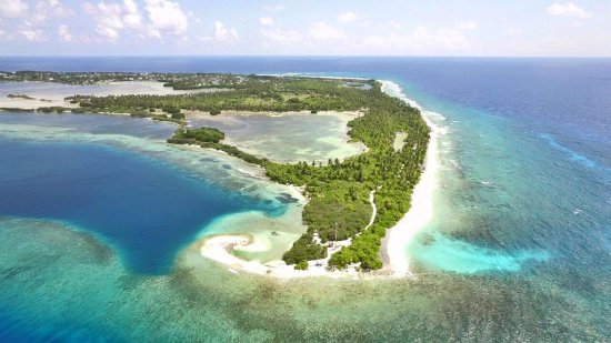 Aerial view of Hithadhoo island in Addu Atoll, Maldives, showing lush green palm forests, turquoise lagoons, and white sandy beaches away from luxury resorts.