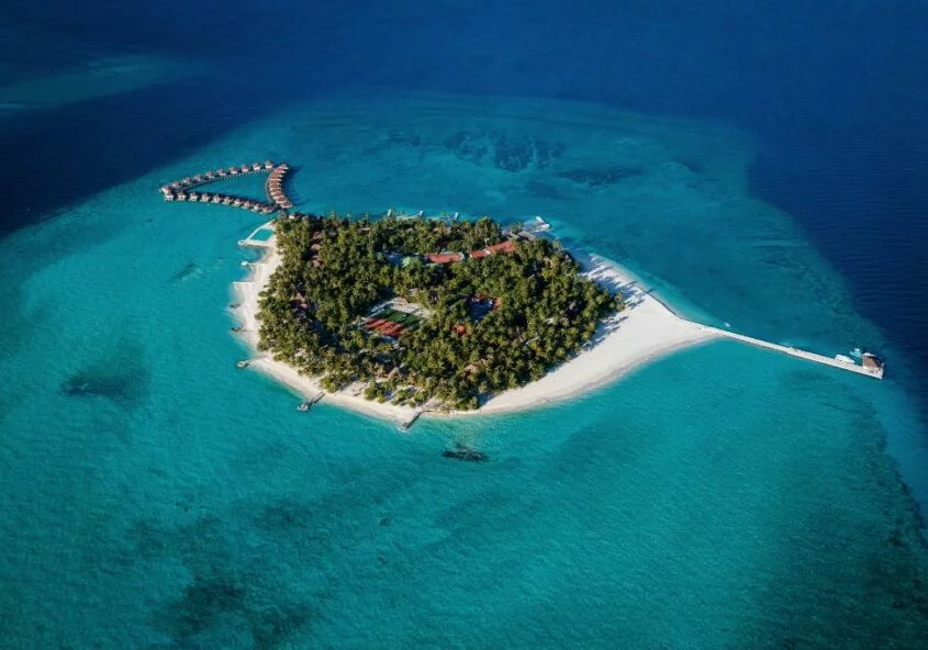 An aerial drone shot of a tropical heart-shaped island in Vaavu Atoll, Maldives, featuring turquoise lagoons, white sandy beaches, and luxury overwater villas.