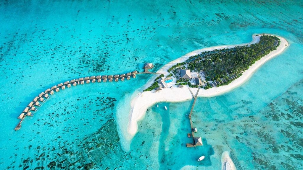 Aerial view of a luxury resort island in Lhaviyani Atoll, Maldives, featuring overwater villas and turquoise lagoons.