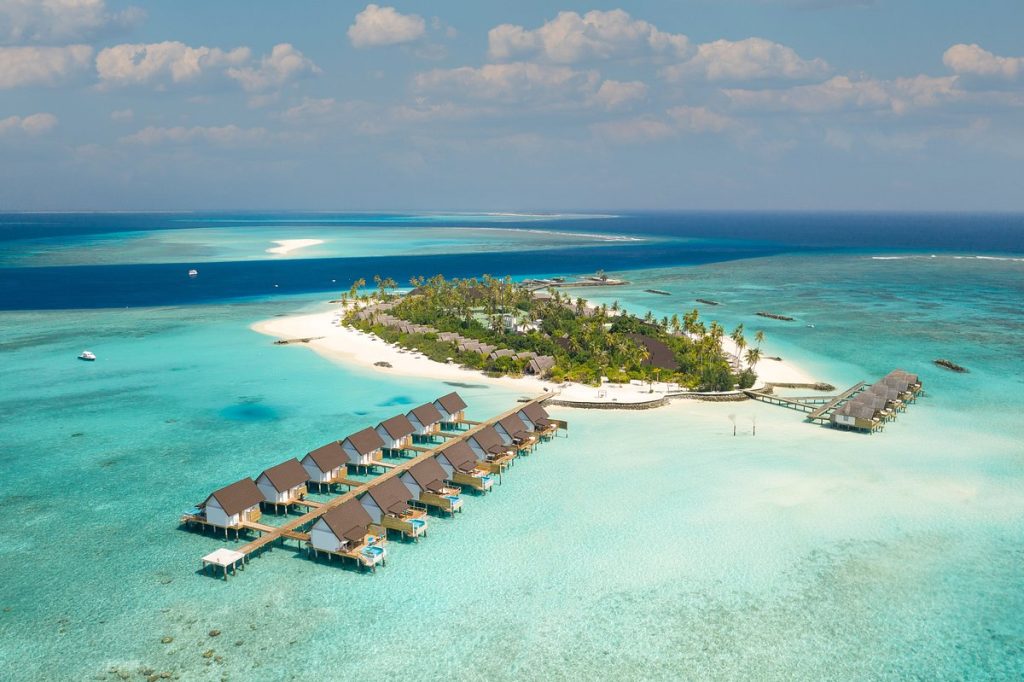 Aerial view of a tropical island resort in Lhaviyani Atoll, Maldives, featuring overwater bungalows and turquoise lagoons.