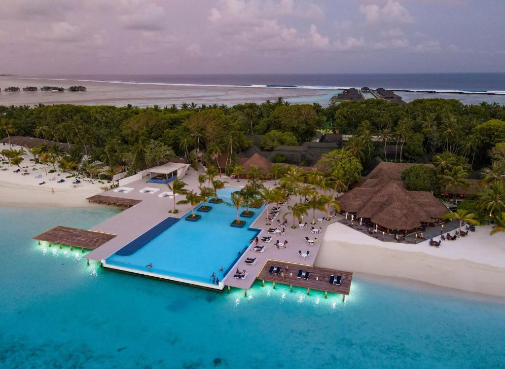 Aerial view of an affordable honeymoon resort in Maldives featuring a luxury infinity pool, white sandy beach, and turquoise ocean water for couples seeking privacy and value.