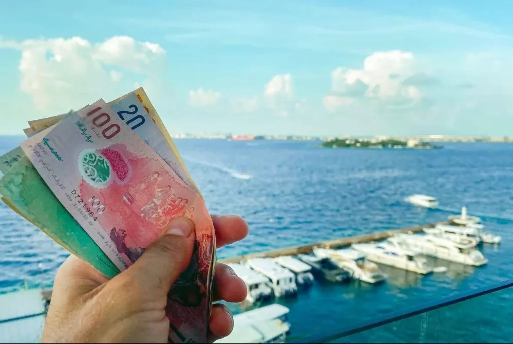 A collection of Maldivian Rufiyaa banknotes and a credit card on a wooden surface, representing Maldives travel money management mistakes.