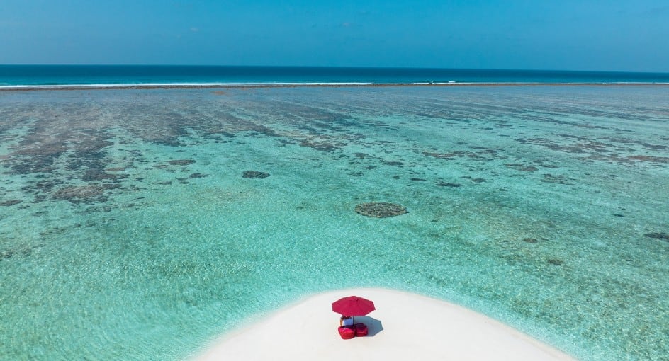 Aerial drone shot of a scenic sandbank and deserted tropical island with turquoise ocean water in Maldives.