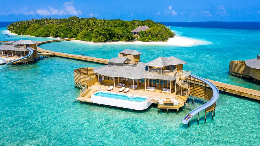 Luxury overwater villa with private pool and water slide into the ocean at Soneva Fushi resort in Baa Atoll, Maldives.