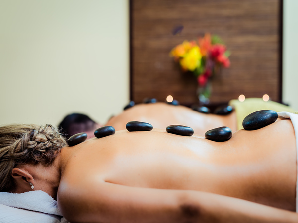 A couple enjoying a rejuvenating hot stone spa therapy at a luxury wellness resort in Raa Atoll, Maldives.