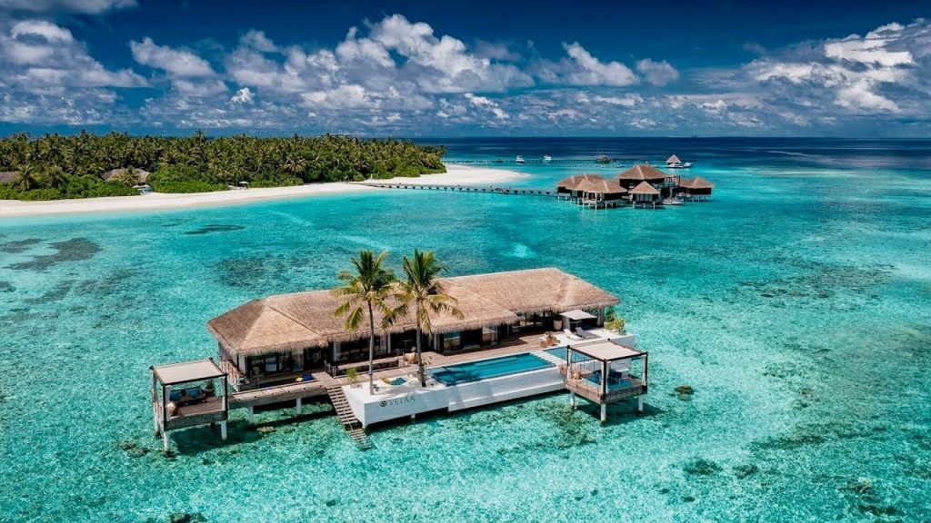 A breathtaking view of an ultra-luxury overwater villa at Velaa Private Island, Maldives, featuring a private infinity pool and crystal-clear turquoise lagoon—perfect for a romantic honeymoon.