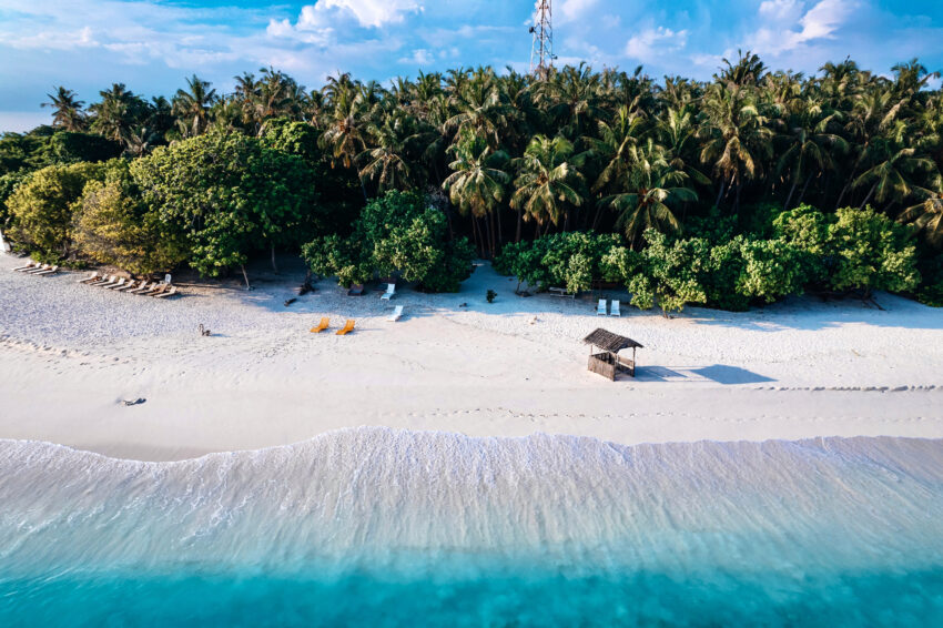 Aerial view of an overwater bungalow and crystal clear turquoise water in Maldives, ideal for first-time visitors.
