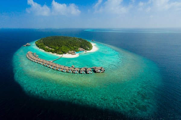 Aerial shot of a luxury island resort in Baa Atoll Maldives featuring a crescent of overwater villas, turquoise lagoon, and white sandy beaches.
