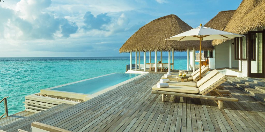 Luxury overwater villa at COMO Maalifushi, Thaa Atoll, featuring a private infinity pool on a wooden deck overlooking the turquoise Indian Ocean in the Maldives.