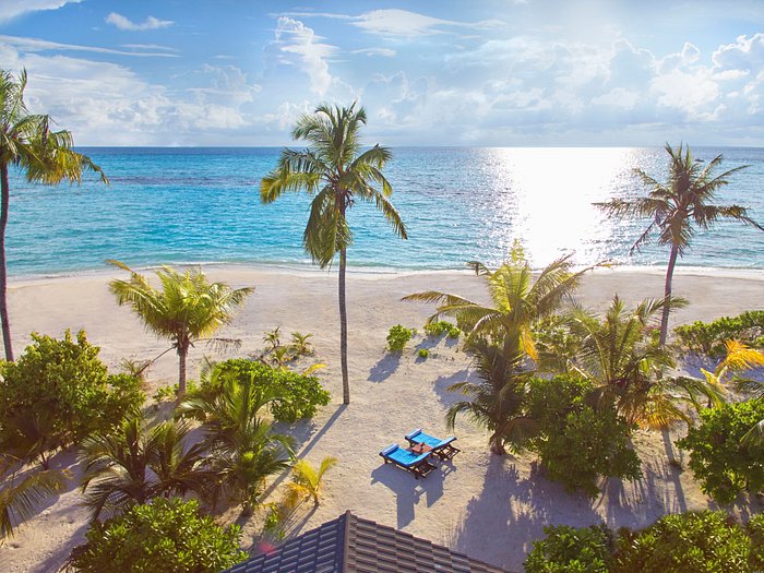 Aerial view of a luxury beach resort in Lhaviyani Atoll, Maldives, featuring white sand, palm trees, and turquoise ocean water.