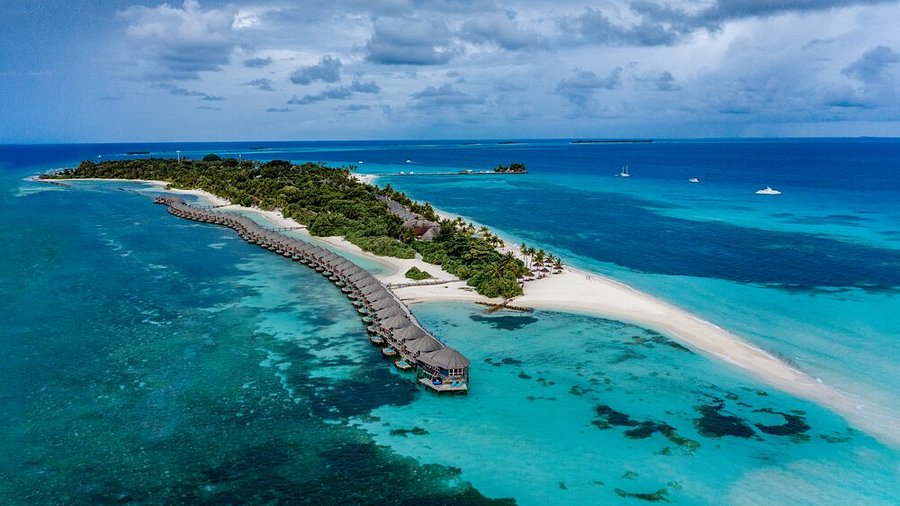 Aerial view of luxury water villas and a white sandbank at Kuredu Island Resort in Lhaviyani Atoll, Maldives.