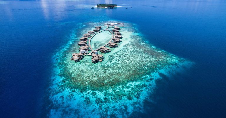 Aerial view of Raffles Maldives Meradhoo overwater villas and house reef in Gaafu Alifu Atoll.