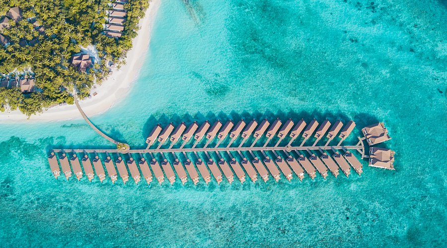 Aerial view of Reethi Faru Resort luxury water villas and turquoise lagoon in Raa Atoll, Maldives.