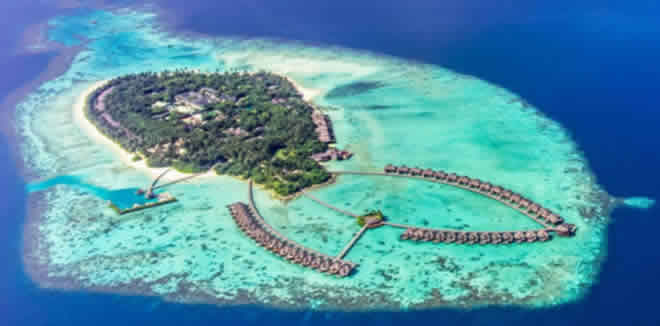 Aerial view of a luxury private island resort with overwater bungalows and turquoise lagoons in Gaafu Alifu Atoll, Maldives.