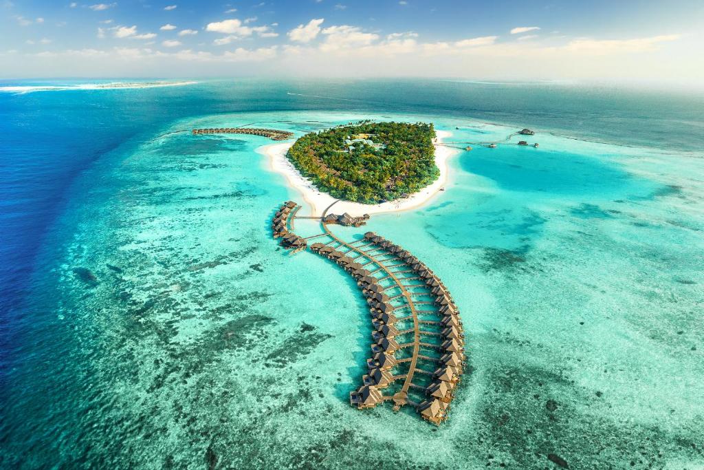 Aerial view of luxury overwater villas and turquoise lagoon at Sun Siyam Iru Fushi resort in Noonu Atoll, Maldives.