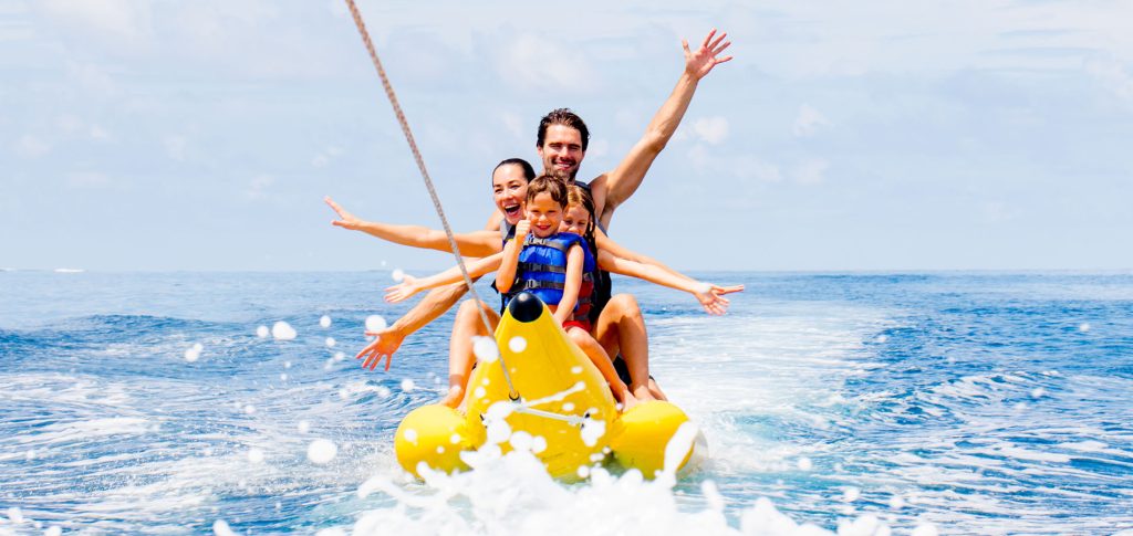 A group of tourists enjoying a banana boat ride in the crystal-clear turquoise waters of Meemu Atoll, Maldives.