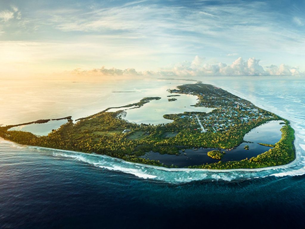 Aerial view of Feydhoo Island in Addu Atoll, Maldives, showing the lush greenery, local township, and turquoise lagoon at sunset.