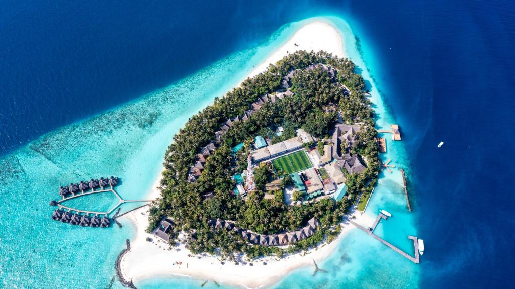 Aerial view of Fihalhohi Island Resort in the Maldives, featuring turquoise lagoons, white sandy beaches, and overwater bungalows near Maafushi.