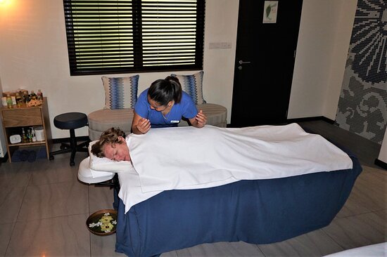 A professional therapist performing a relaxing massage treatment for a guest at a luxury resort spa in Gaafu Dhaalu Atoll.