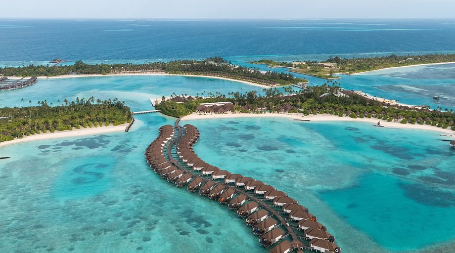 Aerial view of Sun Siyam Olhuveli luxury resort in the Maldives featuring curved overwater villa jetties and turquoise lagoons.
