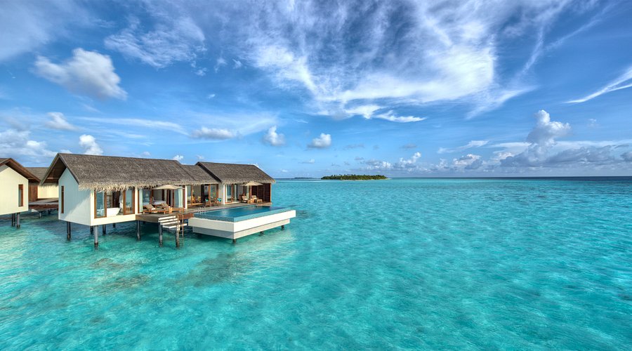 A photo of an overwater bungalow in Gaafu Dhaalu Atoll, Maldives, featuring a private swimming pool, deck, and a stunning view of the turquoise lagoon.