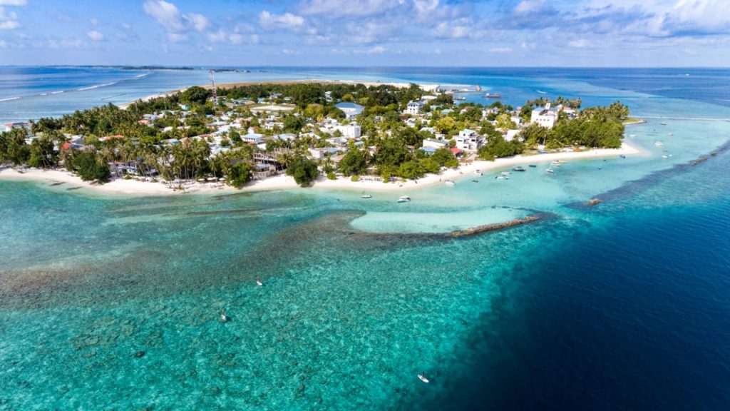 A scenic view of Thulusdhoo Island's turquoise coastline and palm trees, a top-rated budget-friendly local island in the Maldives for 2026 travelers.