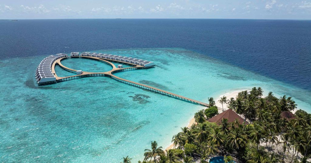 Aerial view of Robinson Maldives luxury adults-only resort in Gaafu Alifu Atoll featuring overwater villas and turquoise house reef.