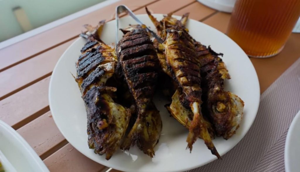 A crisp-skinned fish, cooked hours after it was pulled from the sea - firm white meat stays tender within. This one goes by silver scat around here. Morning sun often finds it beside round flatbreads, though noon heat doesn’t keep folks from serving it just the same.